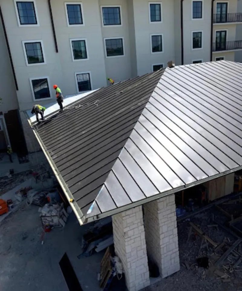 Crew installing standing seam metal roof panels on a commercial project in Somerset